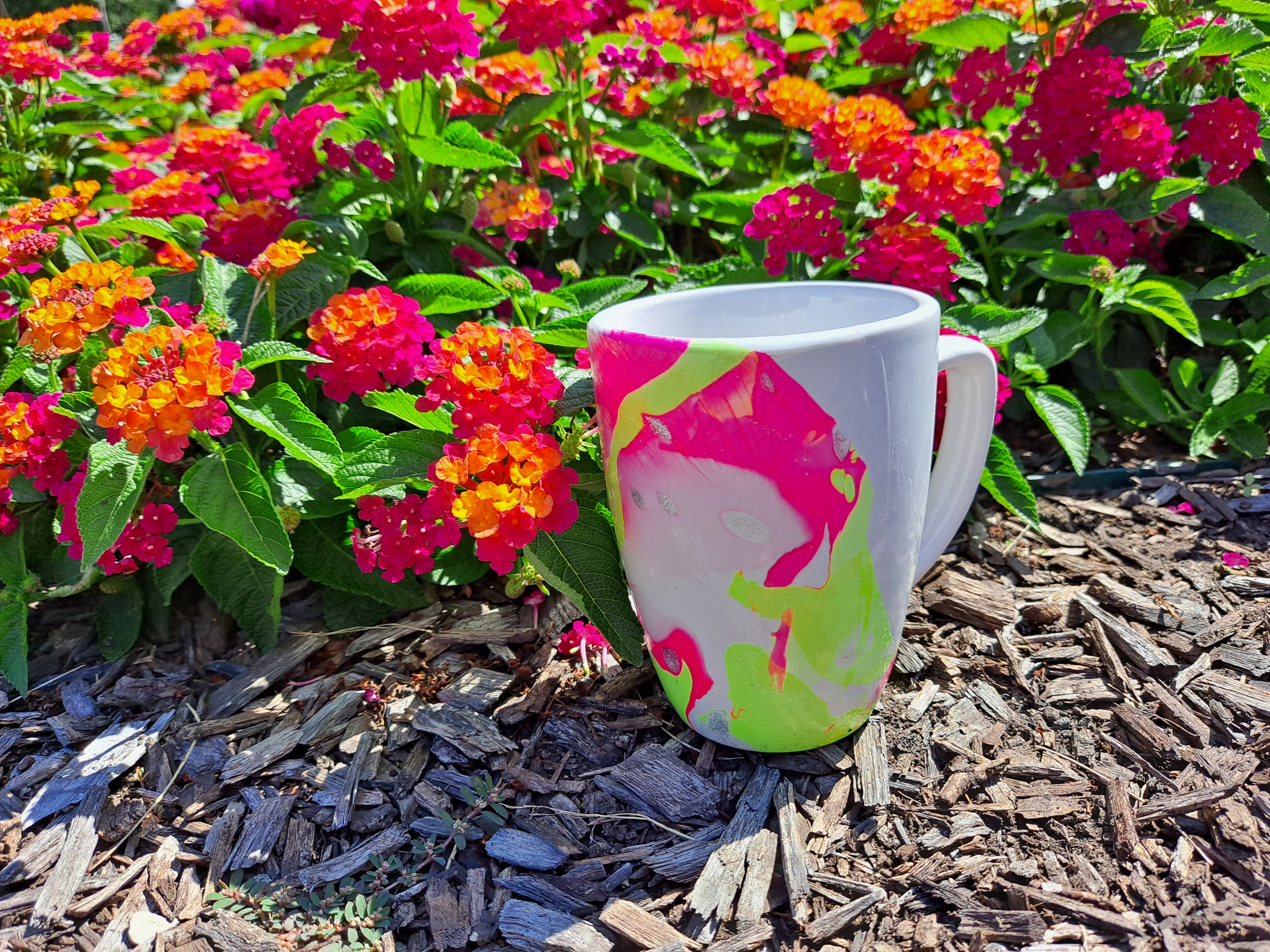 marble pattern on mug, colorful flower bed behind, at the library