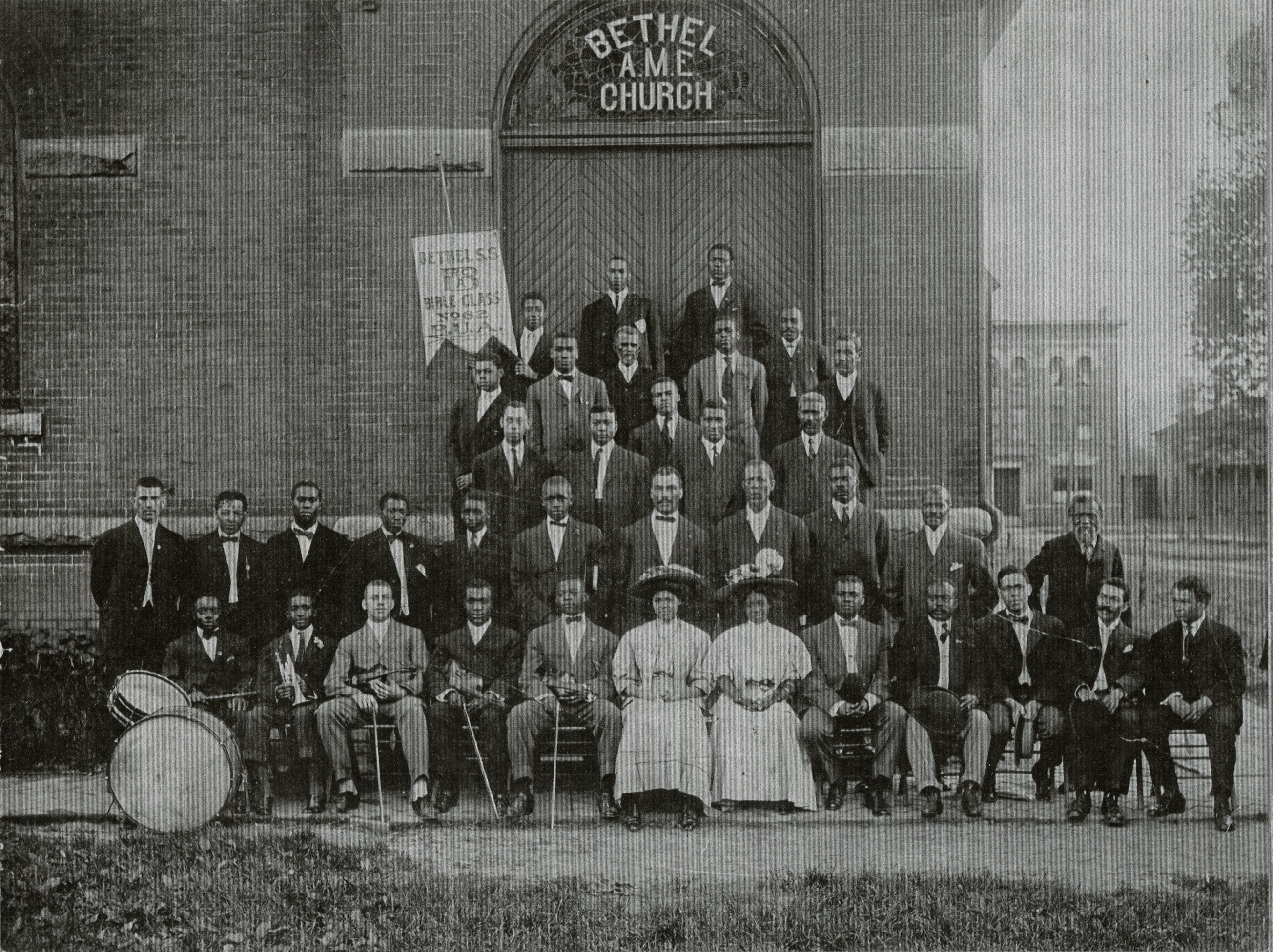 Bethel AME Church group posed on steps including band members, circa 1900