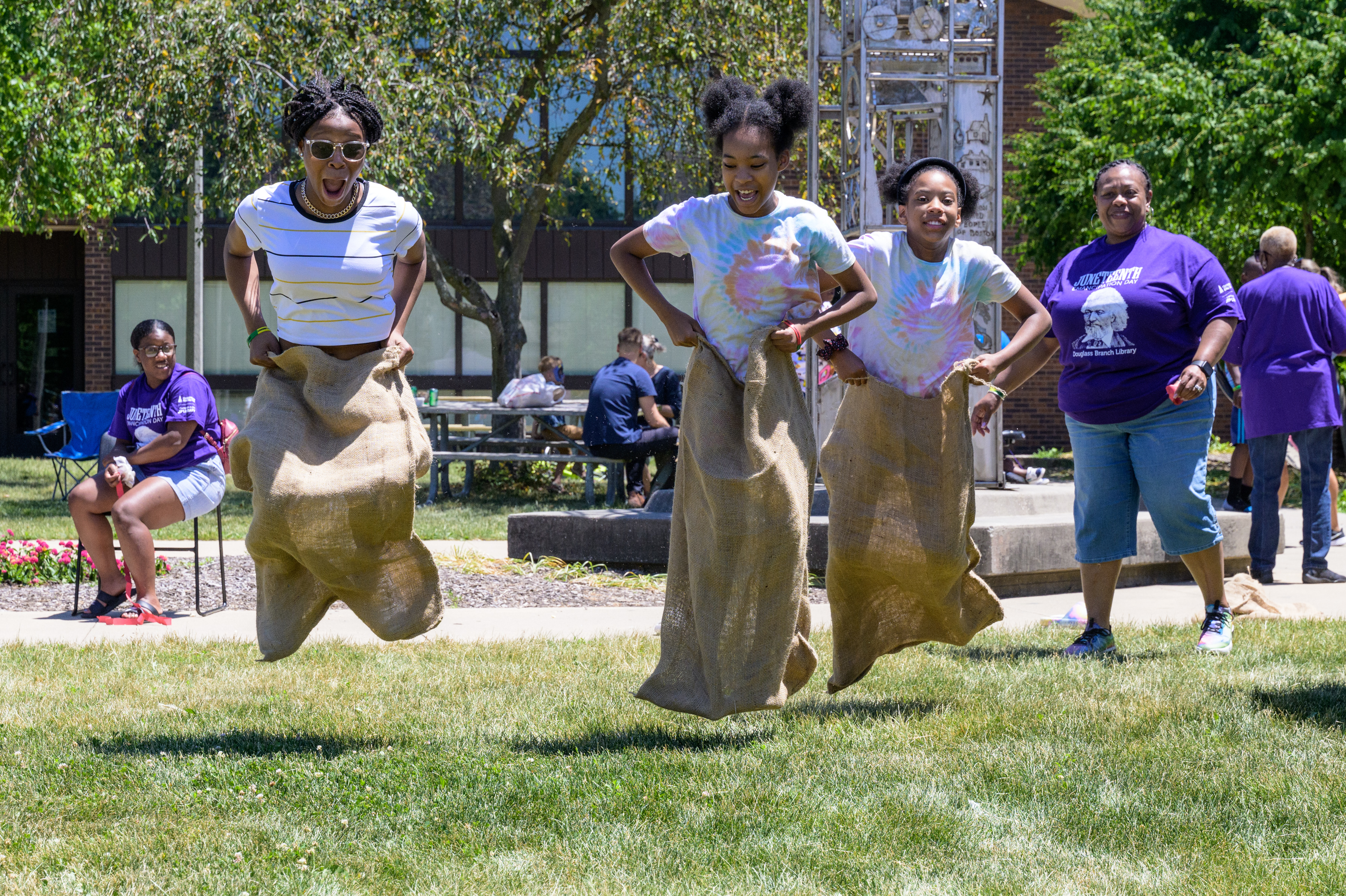 woman, two girls, jumping in  potato sack race in park