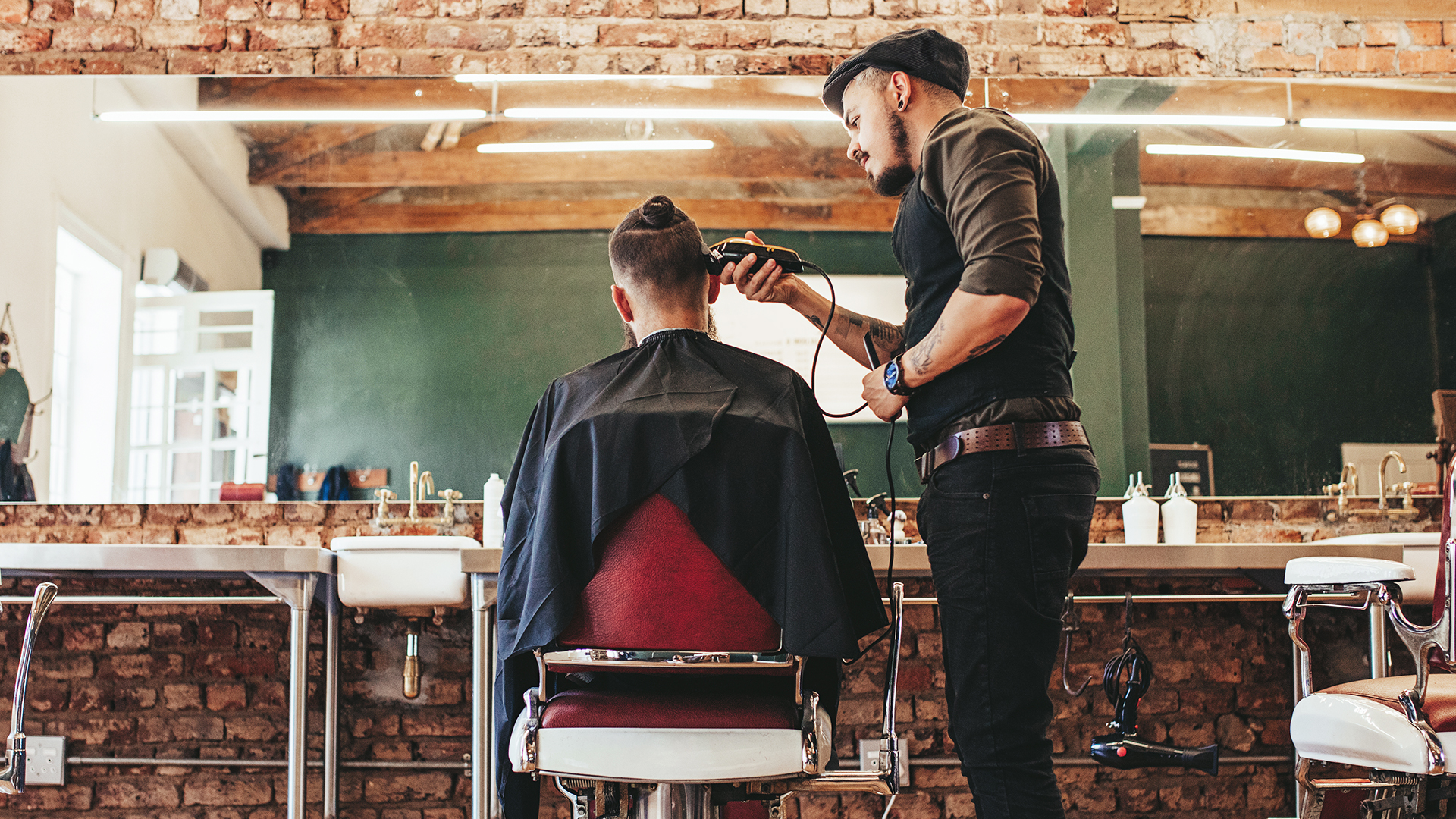 man barber trimming male customer's hair in a salon
