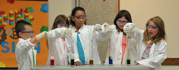 group of young student scientists pouring liquid into beakers