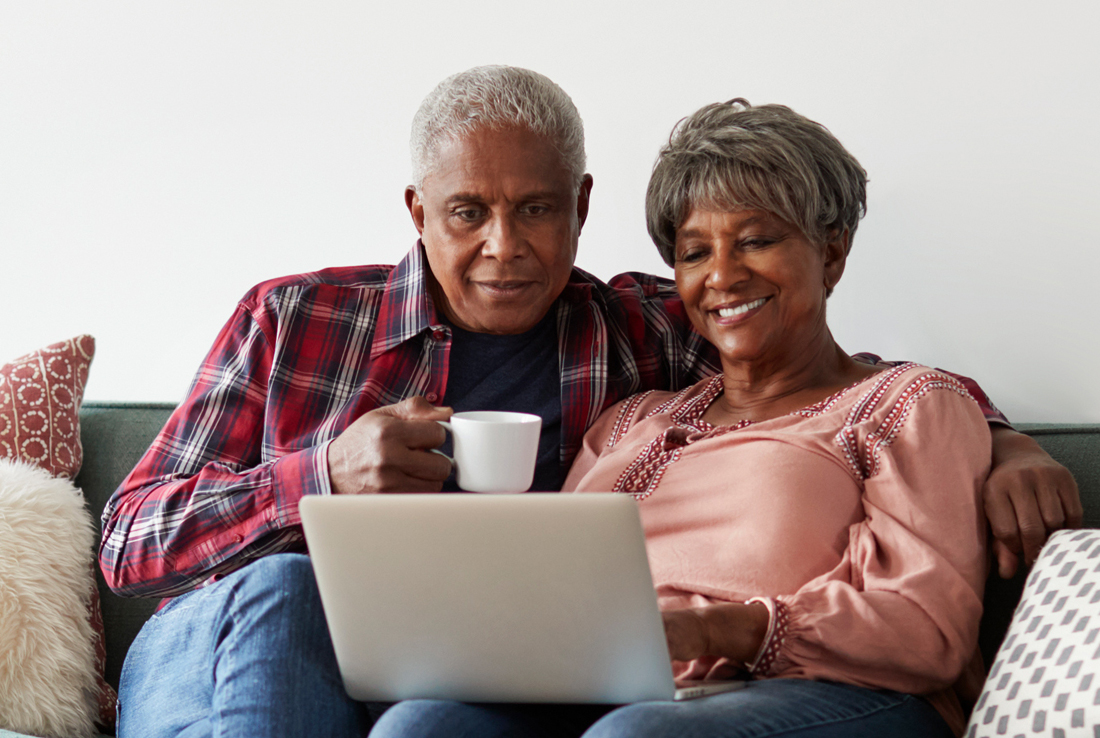 2 seniors sitting on couch at home, looking at laptop, Medicare Help title