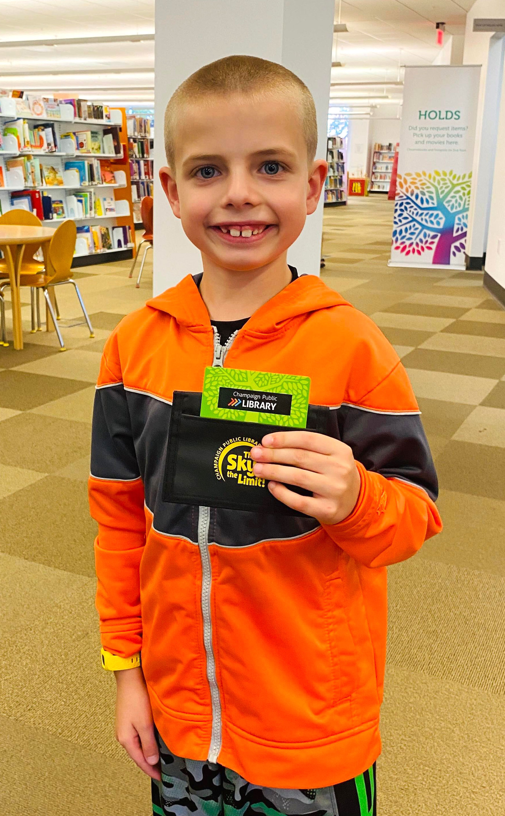4 photos of boy getting first library card and posing by library sign outside