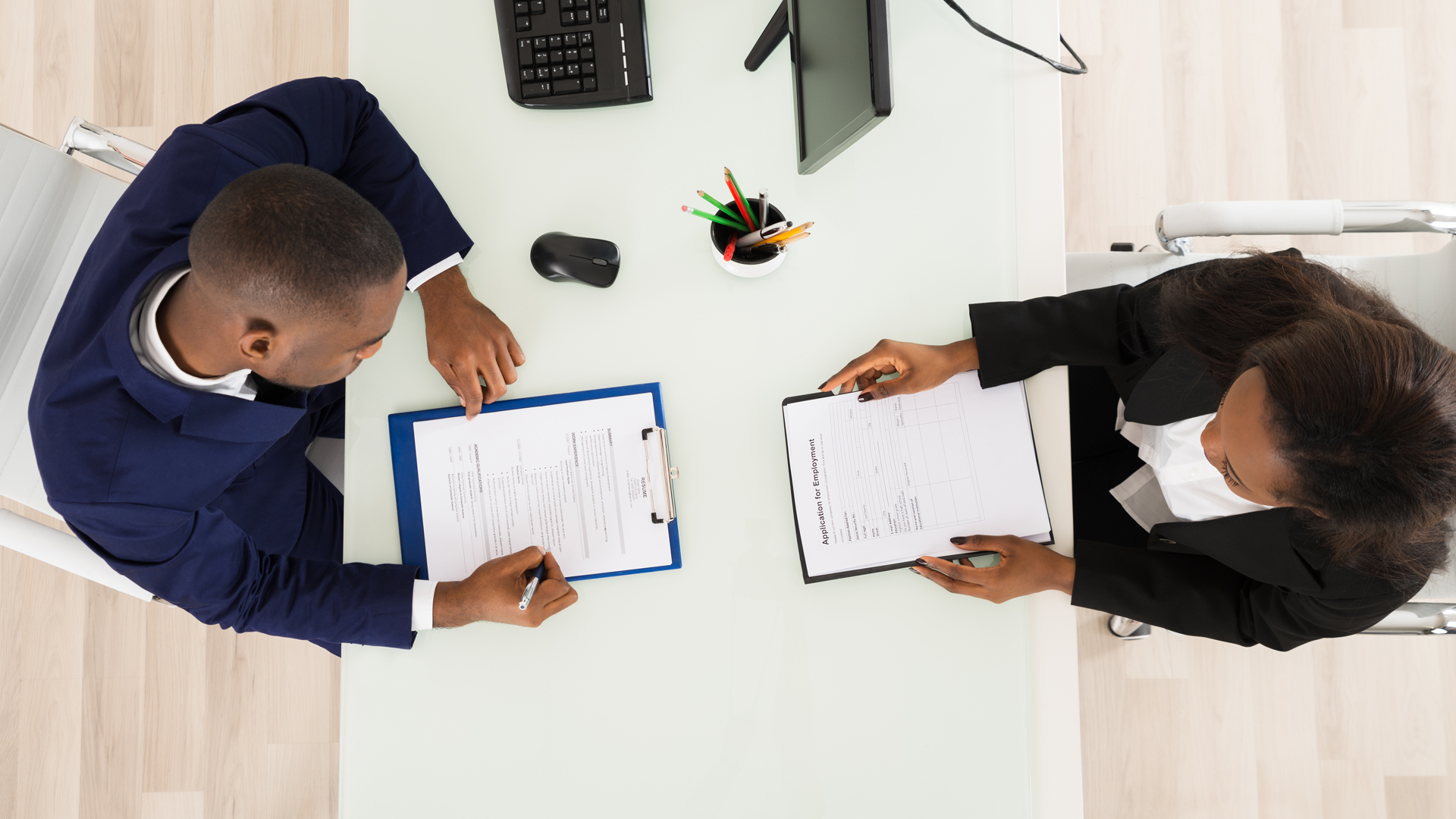 top-down view of two people seated at table discussing resume and job application