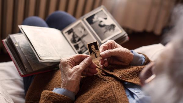 senior's hands holding vintage portrait with old photo album in lap